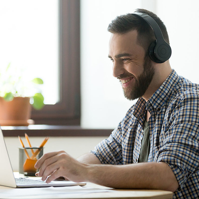 Mann sitzt am Tisch und arbeitet am Laptop