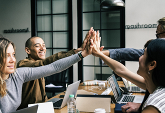 Vier junge Menschen geben sich ein High-Five. 